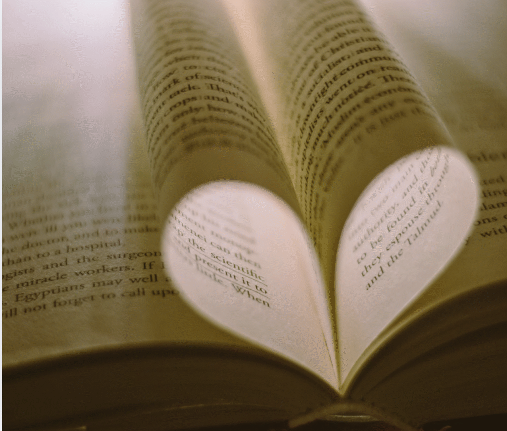 Open book with two pages curved inward to form a heart shape, symbolizing a love of reading and storytelling.